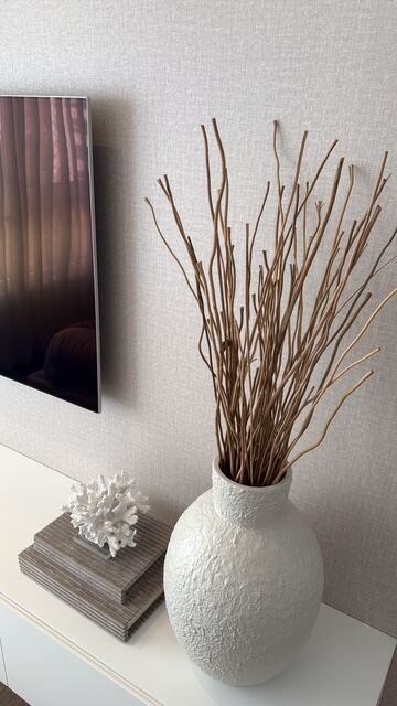 Vaso decorativo branco com galhos secos sobre aparador